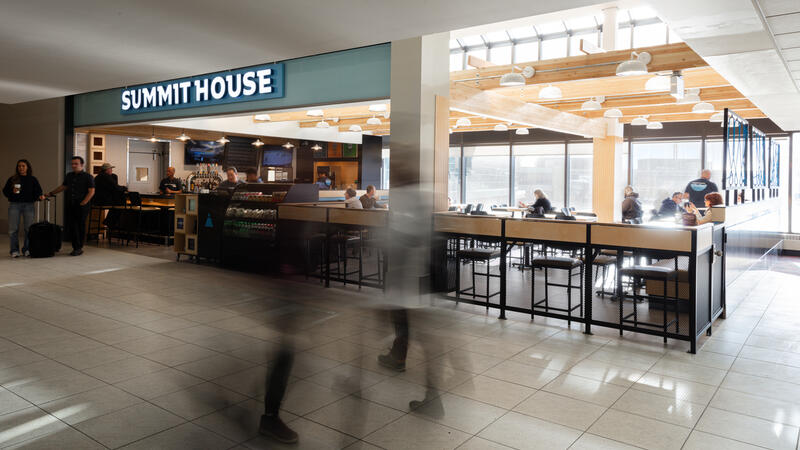 Motion-blurred figures pass before the Summit House airport store