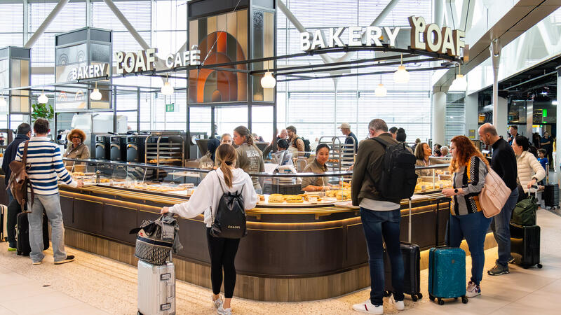 People standing in front of a counter of a store inside the airport.