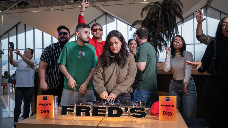 A female dj with people behind her dancing.