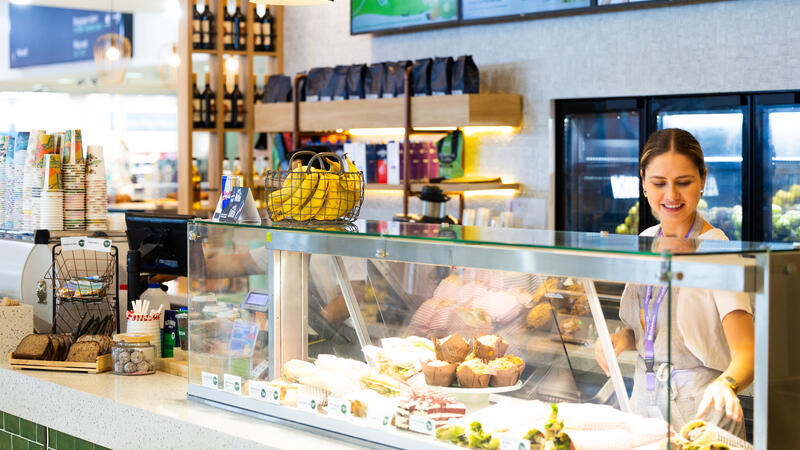 An associate behind a counter and a display window with fresh food.
