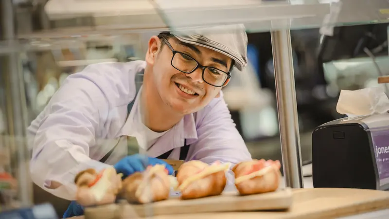 A smiling male associate behind a counter.