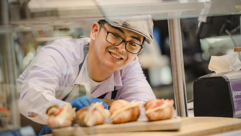 A smiling male associate behind a counter.