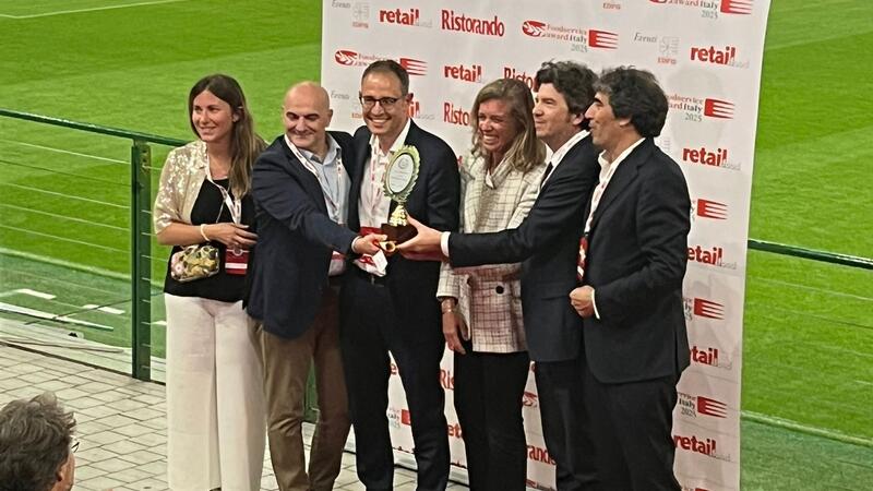 Six people on a stage showing the awards they have received.