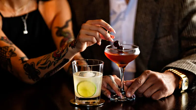 A couple drinking cocktails at the bar.
