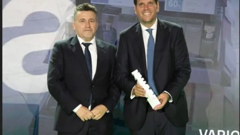 Two men holding a trophy award on a stage