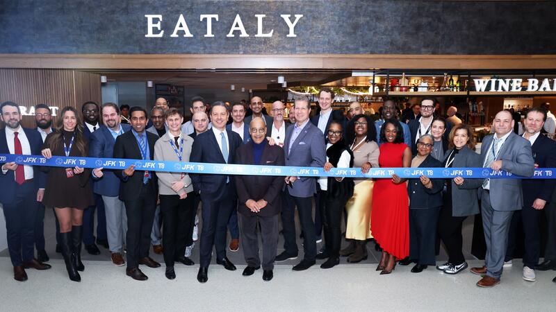 A group of people standing in front of a store for the ribbon cutting