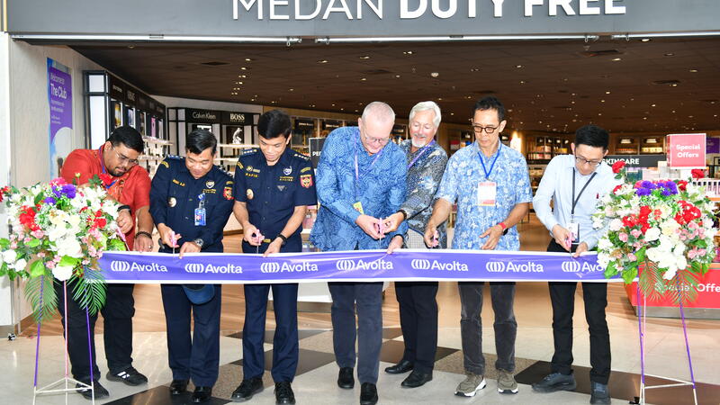 A group of people cutting the ribbon at the opening of a store 