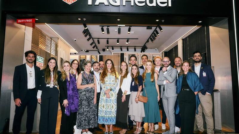 A group of people standing in front of a store to take a group photo