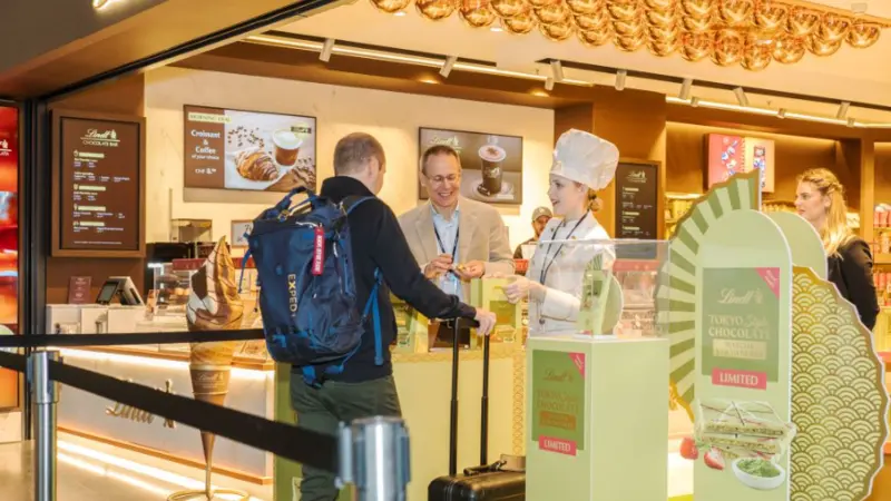 A guy in front of two operators ordering chocolate at a chocolate store
