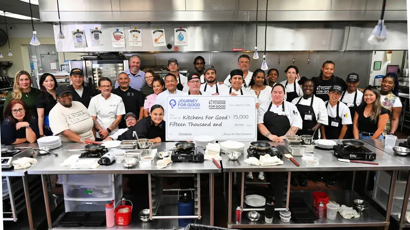 A kitchen team holding a large donation cheque