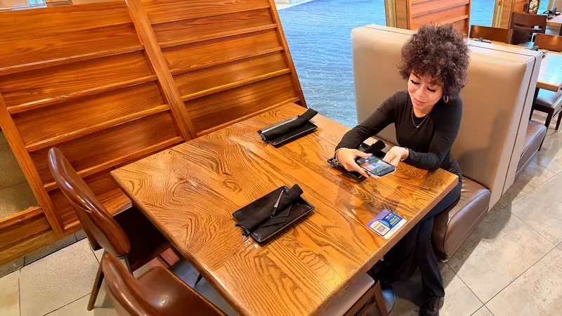 A young woman with curls sitting at a table in a bar