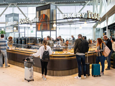 People standing in front of a counter of a store inside the airport.