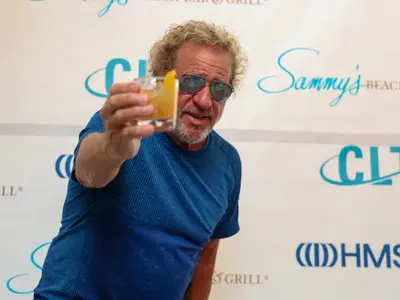 A man with sunglasses celebrate with a toast the opening of a new store.