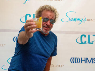 A man with sunglasses celebrate with a toast the opening of a new store.