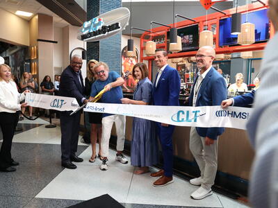A group of people cutting the ribbon for the opening of a restaturant.