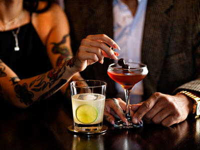 A couple drinking cocktails at the bar.