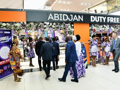 The entrace of a duty free with people passing by
