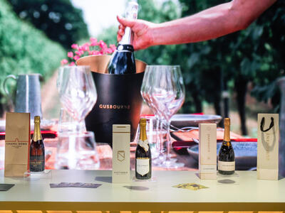 Some bottles of sparkling wines and glasses on a table.