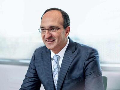 A man with glasses and blak hair wearing a suit