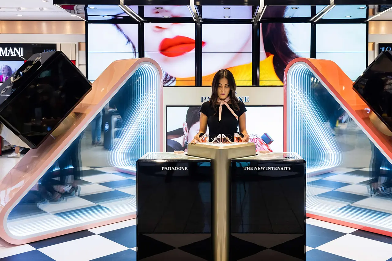 A saleswoman in front of a bright shopping area.