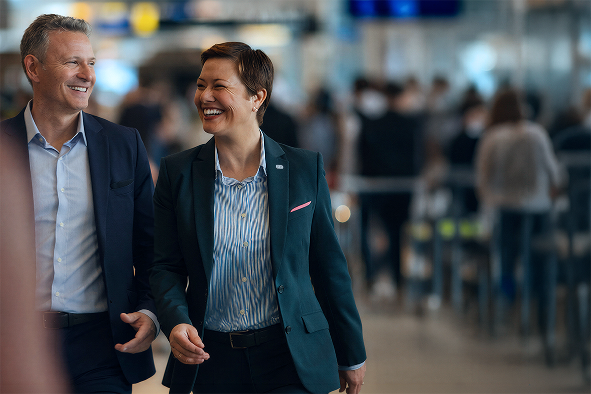 A man and a woman in suits walking and smiling