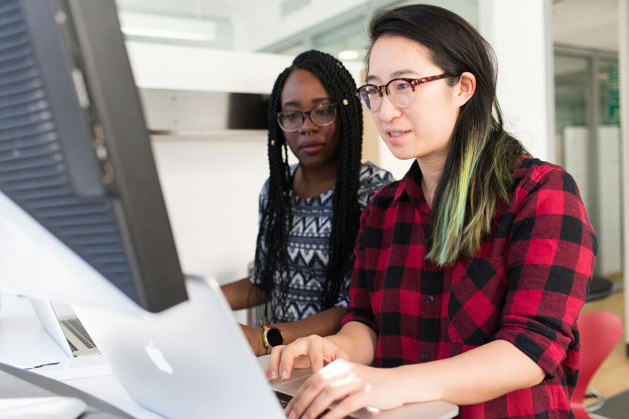Two girls in front of a monitor.