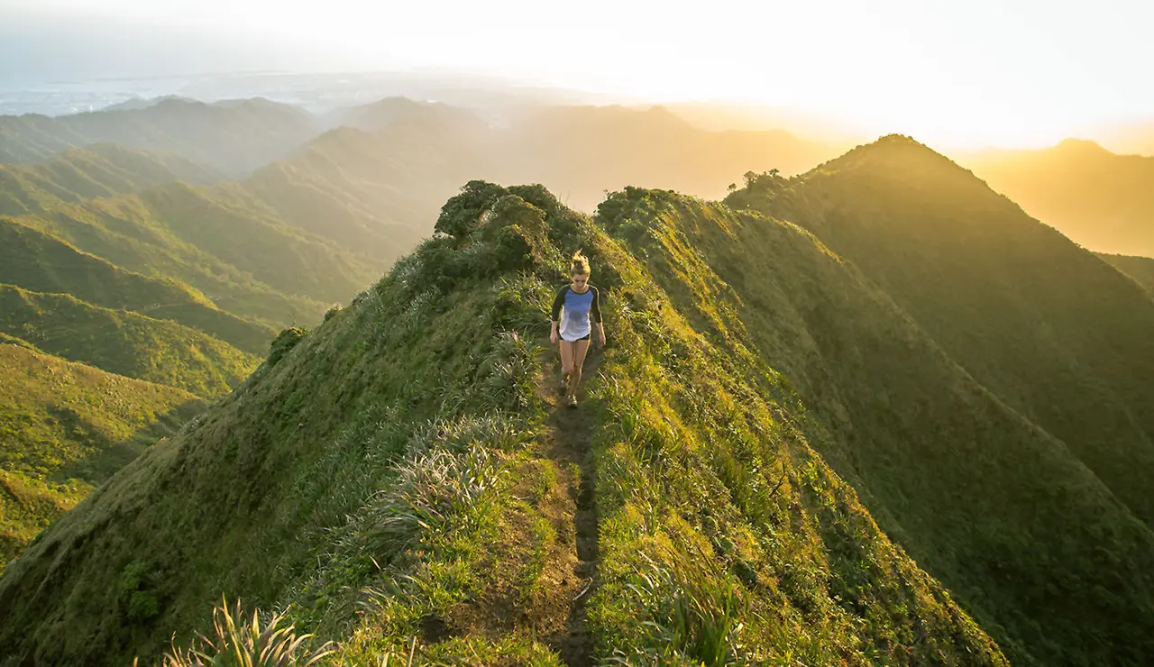 a lady hiking on a very green hill