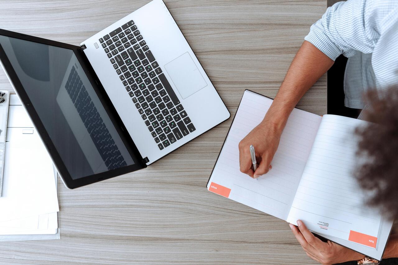 A man sitting at a desk with a laptop and a notebook.