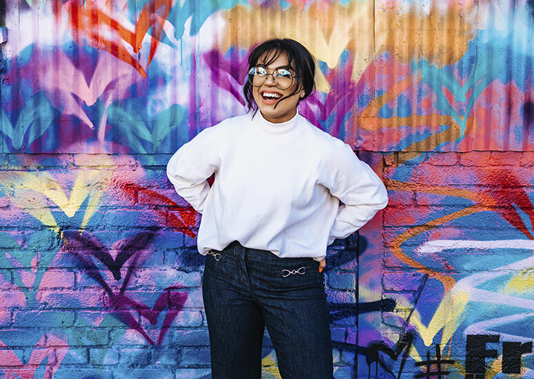 lady with glasses in front of colorful wall